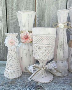 several white vases with flowers and bows are sitting on a wooden table next to each other