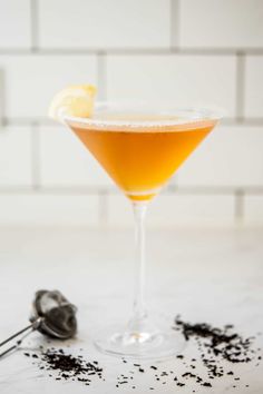 an orange cocktail in a martini glass with black pepper sprinkles on the rim