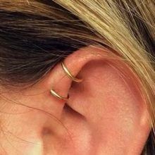 a woman's ear is shown with two small gold rings on the side of her ear