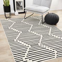 a black and white area rug with lines on the floor next to a gray chair