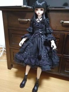 a doll sitting on top of a wooden dresser