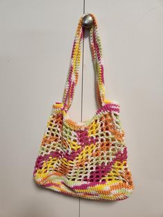 a multicolored crocheted bag hanging from a hook on a white wall