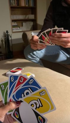 two people sitting on a couch holding playing cards