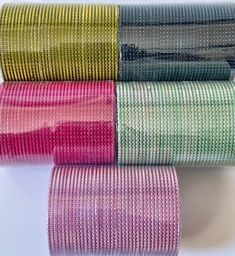 three rolls of colorful woven fabric on a white surface