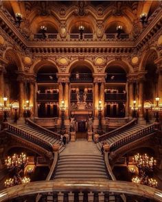 an ornate building with many stairs and chandeliers on the second floor is lit by candles