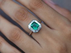 a woman's hand with an emerald ring on it