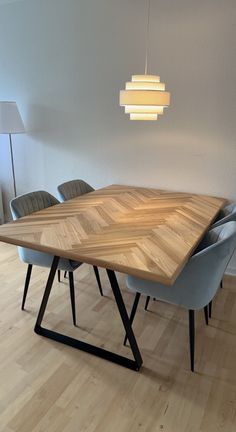 a wooden table surrounded by blue chairs in a room with white walls and wood flooring