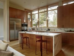 a kitchen with wooden cabinets and marble counter tops, along with two bar stools