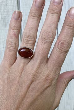 A rich dark blood red orange carnelian has been set in sterling silver with a handmade ring band from sterling silver half dome wire. This stone has inner crystals of differing color that show throughout-it is not a solid blood red orange. The stone has been set horizontally (east to west) and is 13mm x 18mm in size and about 5-6mm in height. It is also available in a vertical (north to south) setting. Made to order! Chose your size and setting direction at checkout! Carnelian brings out hidden Red Carnelian Oval Cabochon Ruby Ring, Oval Carnelian Jewelry With Polished Finish, Polished Oval Carnelian Jewelry, Classic Oval Carnelian Jewelry, Oval Amber Agate Ring, Amber Oval Agate Ring, Oval Red Carnelian Jewelry, Polished Carnelian Oval Rings, Handmade Oval Carnelian Ring