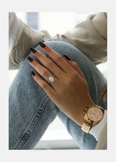 a woman's hand with black nails and a gold watch on her left wrist