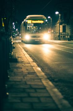 a bus is driving down the street at night with its headlights on and it's lights turned on