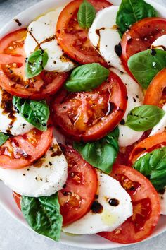 a white plate topped with sliced tomatoes and mozzarella