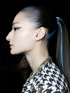 a woman with blue hair and ponytails on the catwalk at a fashion show