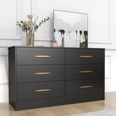 a large black dresser with gold handles and drawers in front of a white paneled wall