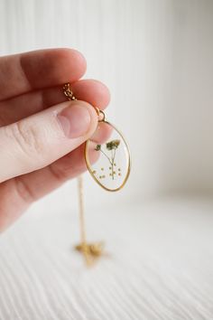 This 18k gold plated stainless steel chain has real babies breath flowers preserved in resin inside of it! Each necklace is one of a kind and is such a gorgeous, feminine piece. As always, this necklace is also hypoallergenic and nickel free. AND if you like a matching set, pair it with the Pressed Flower Pendant Hoop in White! This necklace is adjustable from 16-18 inches in length. Delicate Oval Jewelry With Pressed Flowers, Delicate Oval Pressed Flower Jewelry, Delicate Pressed Flowers Jewelry For Everyday, Dainty Necklace With Natural Inclusions For Gifting, Everyday Gold Jewelry With Pressed Flowers, Delicate Gold Necklace With Pressed Flowers, Nature-inspired Gold Necklace With Oval Pendant, Pressed Flowers Necklace With Oval Pendant As Gift, Gold Pressed Flower Necklace Gift For Her