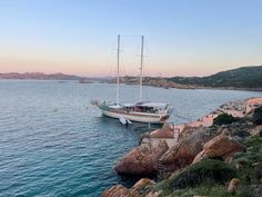 a sailboat is docked on the water near some rocks