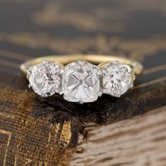 A trilogy ring that showcases the best of the old cut world! A chunky and charming old mine cushion cut diamond is flanked by 2 beautifully matched old European cuts on the shoulders. Set in our Victorian-inspired trilogy setting, the ring is the perfect combo of old cut diamonds in a setting with clean lines yet retaining vintage vibes.Platinum and 18kt yellow gold. Size 6, and fully sizable.Central diamond measures 7.14 x 5.81 x 4.78 mmGIA report on center stone hereOld European cut diamonds o Luxury Heirloom Wedding Rings, Diamond Ring Trilogy, Engagement Ring Trends 2000’s, Luxury Heirloom Wedding Ring With Brilliant Cut, Heirloom Wedding And Engagement Jewelry With Single Cut Diamonds, Heirloom Diamond Ring For Anniversary, Luxury Heirloom Style Ring, Antique Diamond Wedding Bands, 1950s Engagement Ring