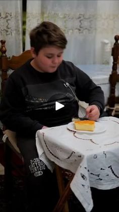 a young boy sitting at a table with a piece of cake