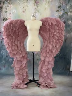 a mannequin with pink feathers on it's legs and arms in front of a floral background