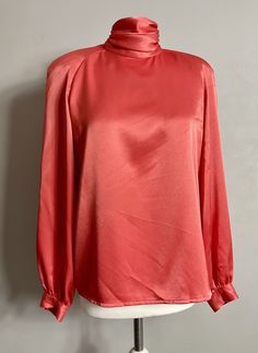 Beautiful vintage satin blouse by Alternatives in size UK 12 High neck Open cowl back Padded shoulder Long sleeve In coral satin Great used condition Silk High Neck Top For Evening, High Neck Blouse For Spring Formal Events, High Neck Blouse For Spring Formal Occasions, Elegant High Neck Satin Top, High Neck Spring Blouse, Pink Satin Top For Evening, Chic Red Satin Blouse, Formal Pink Satin Tops, Long Sleeve Pink Satin Top