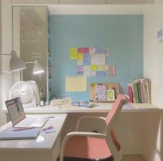 a desk with a laptop computer sitting on top of it next to a wall covered in sticky notes