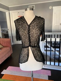 "1930's sheer black lace short sleeve blouse with a high low hem. Black covered buttons up the front. In largely good condition, but does have two holes in the lace, one at the waist and a large hole in the right shoulder. See all photos Womens small 34\" bust 28\" waist 17\" shoulder to waist seam 15\" back waist to the back hem" Black Lace Short Sleeve Tops, Black Lace Top With Short Sleeves, Fitted Short Sleeve Top With Delicate Lace, Fitted Tops With Delicate Lace And Short Sleeves, Fitted Sheer Lace Top With Short Sleeves, Black Lace Top With Lace Work, Fitted Lace Top With Short Sleeves, Formal Short Sleeve Lace Top, Fitted Scalloped Lace Short Sleeve Blouse