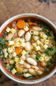 a bowl filled with pasta and vegetables on top of a wooden table