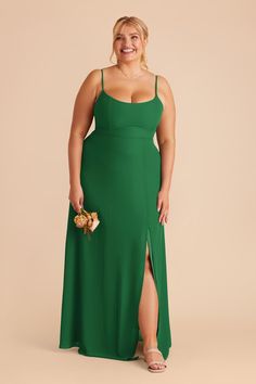 a woman in a green dress with her legs slited up and holding a bouquet