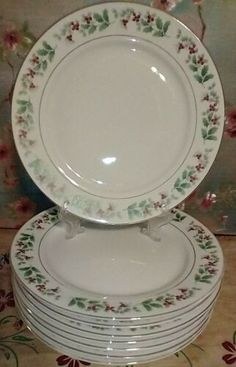 a stack of white plates sitting on top of each other in front of a floral wallpaper