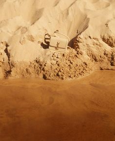 a white suitcase sitting in the sand at the beach