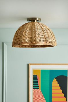 a wicker light hanging from the ceiling over a bed in a room with blue walls