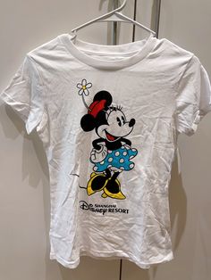 a white t - shirt with a cartoon mickey mouse on it hanging from a hanger