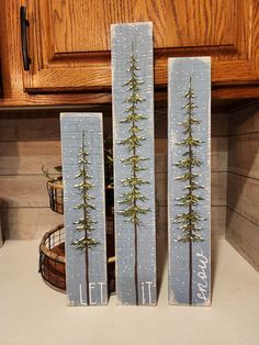 two wooden blocks with trees painted on them sitting on a counter top next to a basket