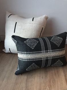 two black and white pillows sitting on top of a wooden floor next to each other