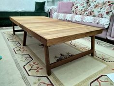 a wooden table sitting on top of a rug in front of a couch and loveseat