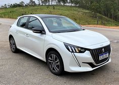 a white car is parked on the side of the road in front of a hill