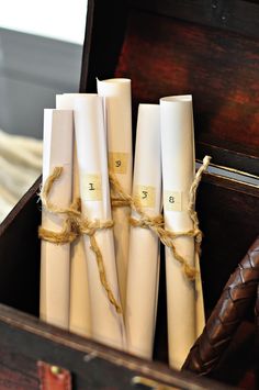 four white candles are tied together in a wooden box with brown leather handles and rope