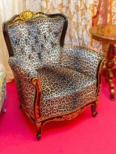 a leopard print chair sitting on top of a pink floor next to a wooden table