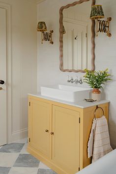 a bathroom with yellow cabinets and a white sink