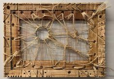 an art piece made out of wood and rope with a square hole in the middle