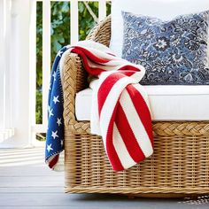 an american flag blanket sitting on top of a wicker chair next to a pillow