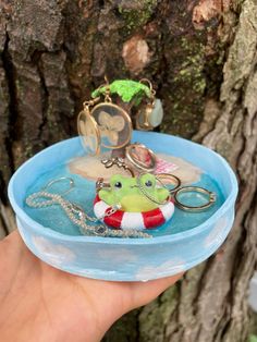 a hand holding a blue bowl with keychains in it and an octopus on the bottom