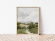 a watercolor painting with a quote on it in front of a white wall and wooden floor