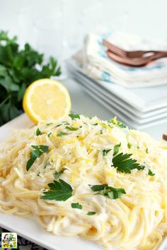 a white plate topped with pasta and garnished with parsley next to silverware