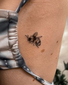 a small bee tattoo on the back of a woman's thigh