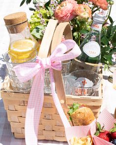 a picnic basket filled with food and drinks sitting on a table next to some flowers