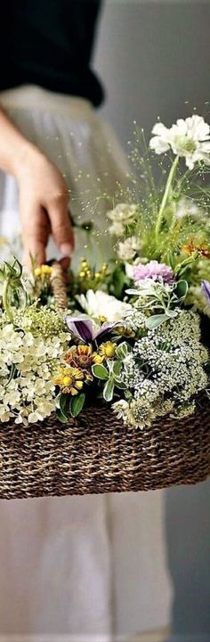 a person holding a basket with flowers on it