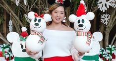 a woman holding two stuffed animals in front of christmas decorations