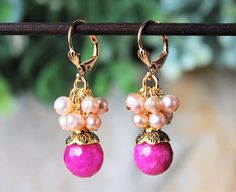 "This lovely pair of earrings features hot pink jade gemstone, which are accented with an ornate pewter bead cap, plated in 24 karat gold. This striking color combination is offset with beautiful clusters of champagne freshwater pearls. Hanging from a surgical steel lever-back, it measures 1 ¼\" in length. Earrings are light weight and sway gracefully as you move about your day. These stunning dangle earrings are unique, feminine and eye-catching, a great accent to any wardrobe. Also available i Pink Gemstone Jewelry For Jewelry Making, Pink Gemstone Dangle Jewelry, Pink Gemstone Drop Earrings, Adjustable Pink Pearl Drop Earrings, Pink Adjustable Pearl Drop Earrings, Nickel-free Pink Wedding Jewelry, Pink Drop Earrings With Natural Stones, Pink Natural Stones Drop Earrings, Pink Natural Stone Drop Earrings