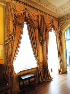 a large window with drapes and curtains on the windowsill in an ornately decorated room